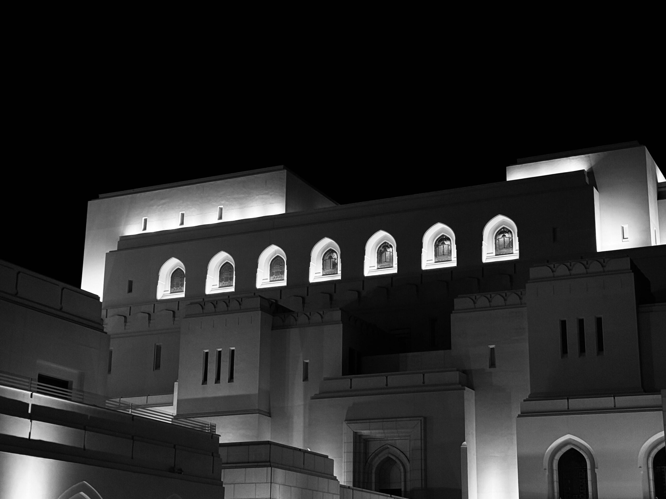 Elegant night view of the Royal Opera House Muscat with architectural illumination captured in monochrome.