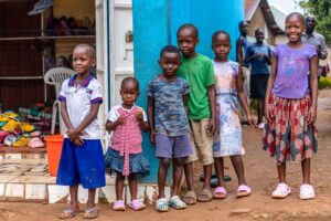 A heartwarming scene of smiling children standing outdoors in bright outfits, showcasing joy and diversity.