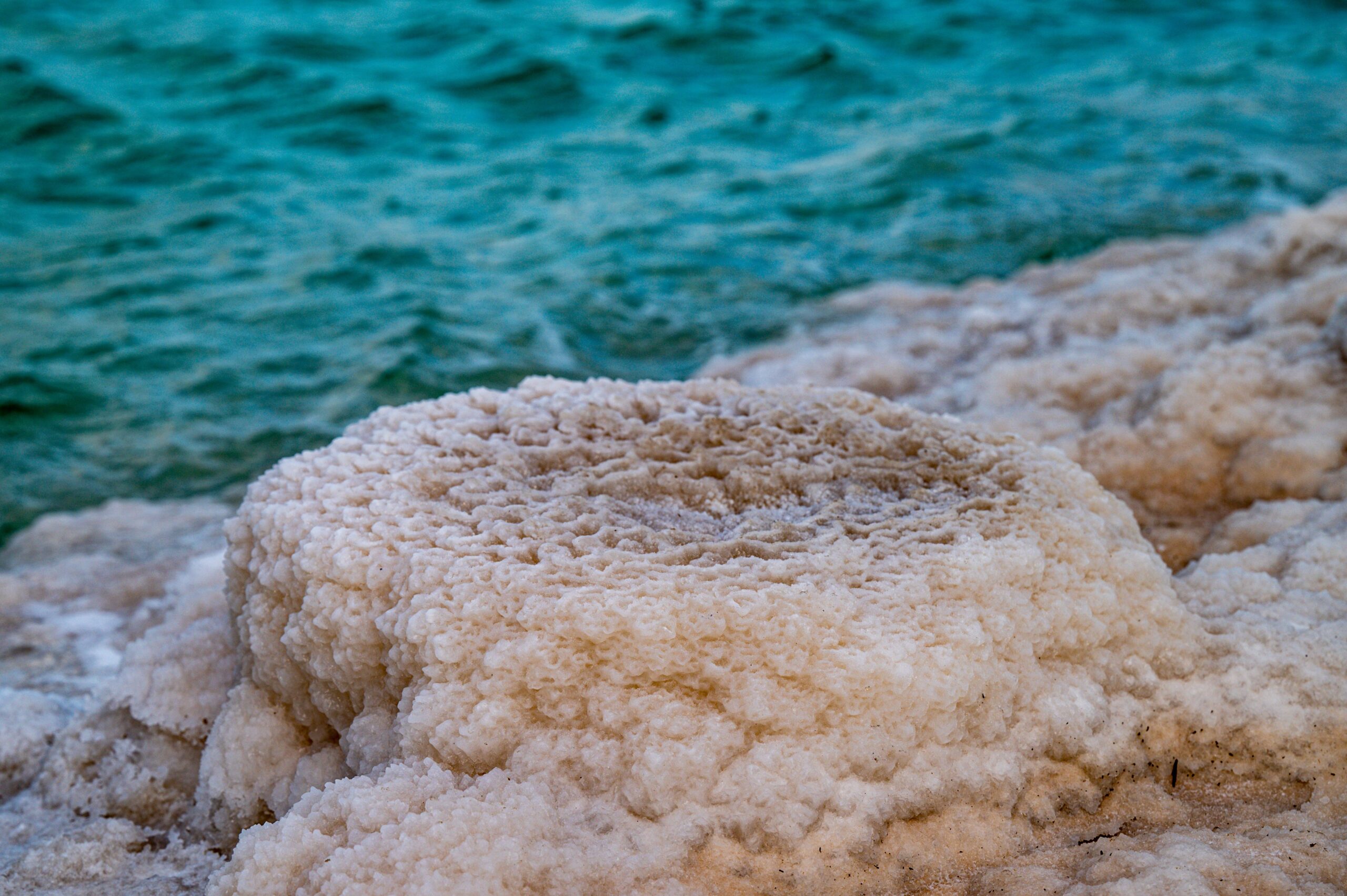 Close-up view of salt formations along a vibrant blue shoreline, showcasing natural textures.